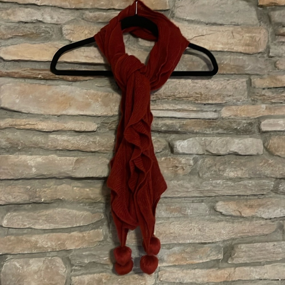 Red scarf with cascading ruffles and Pom poms on the ends.